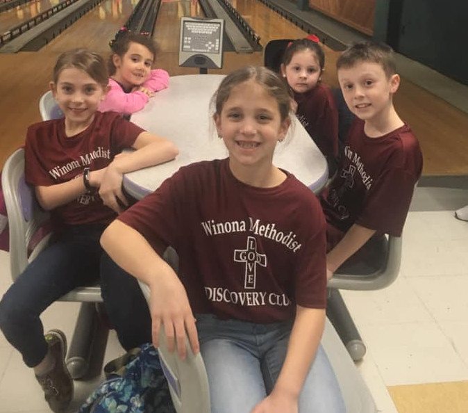 Discovery Club kids in matching shirts at a bowling outing
