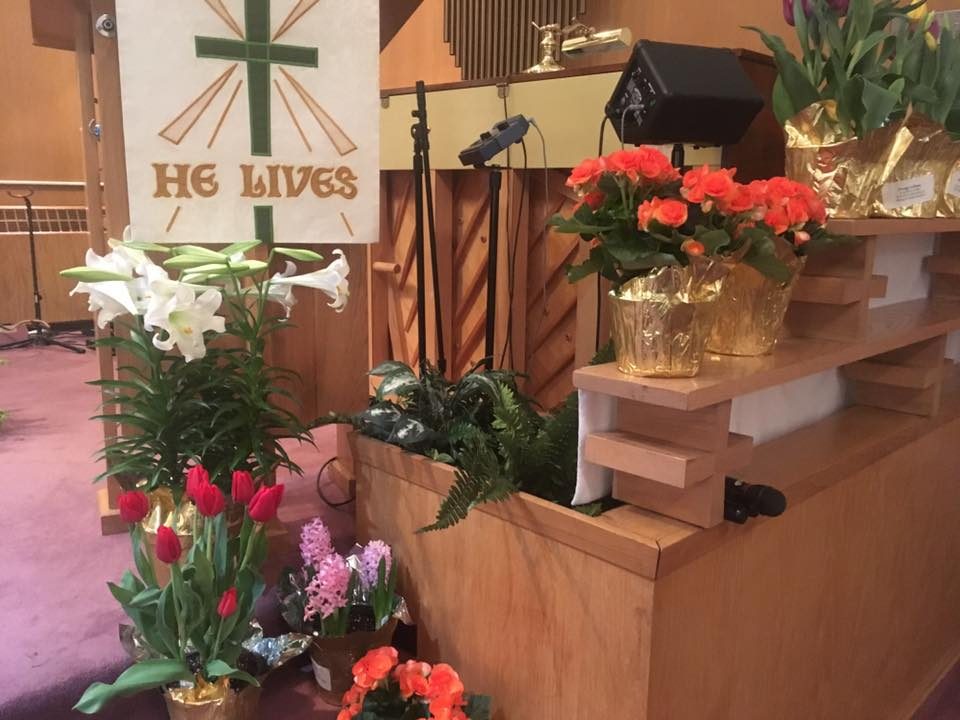 Easter lilies and spring flowers beside a He Lives banner